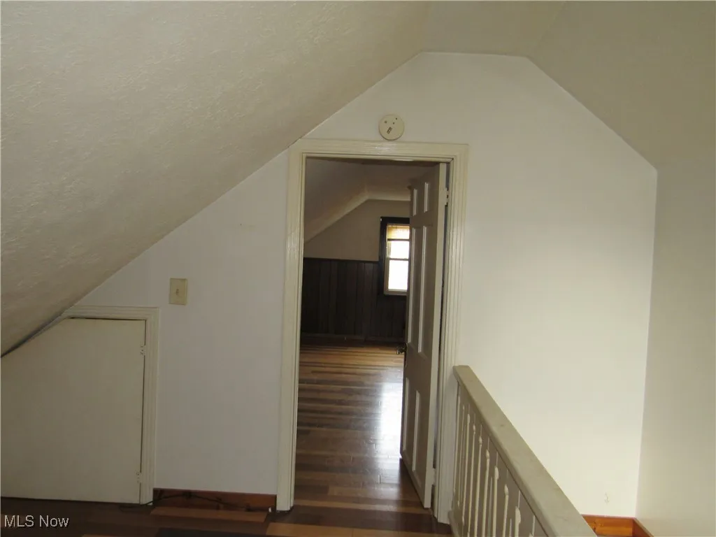 Additional living space featuring dark wood finished floors and vaulted ceiling
