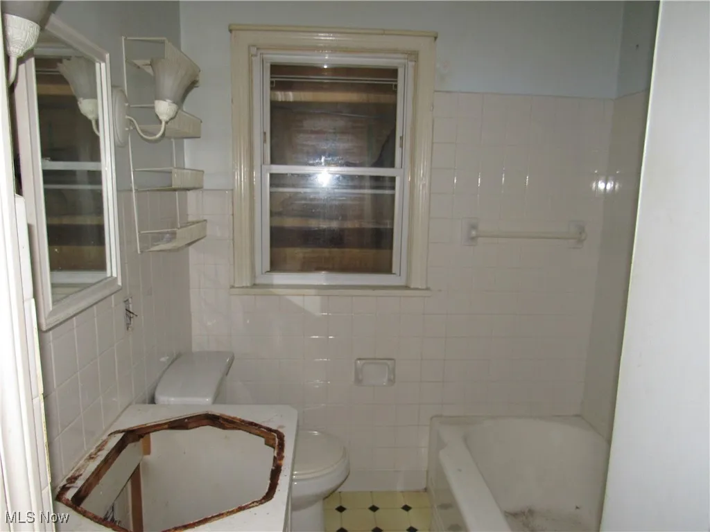 Bathroom featuring vanity, a bathtub, and tile walls