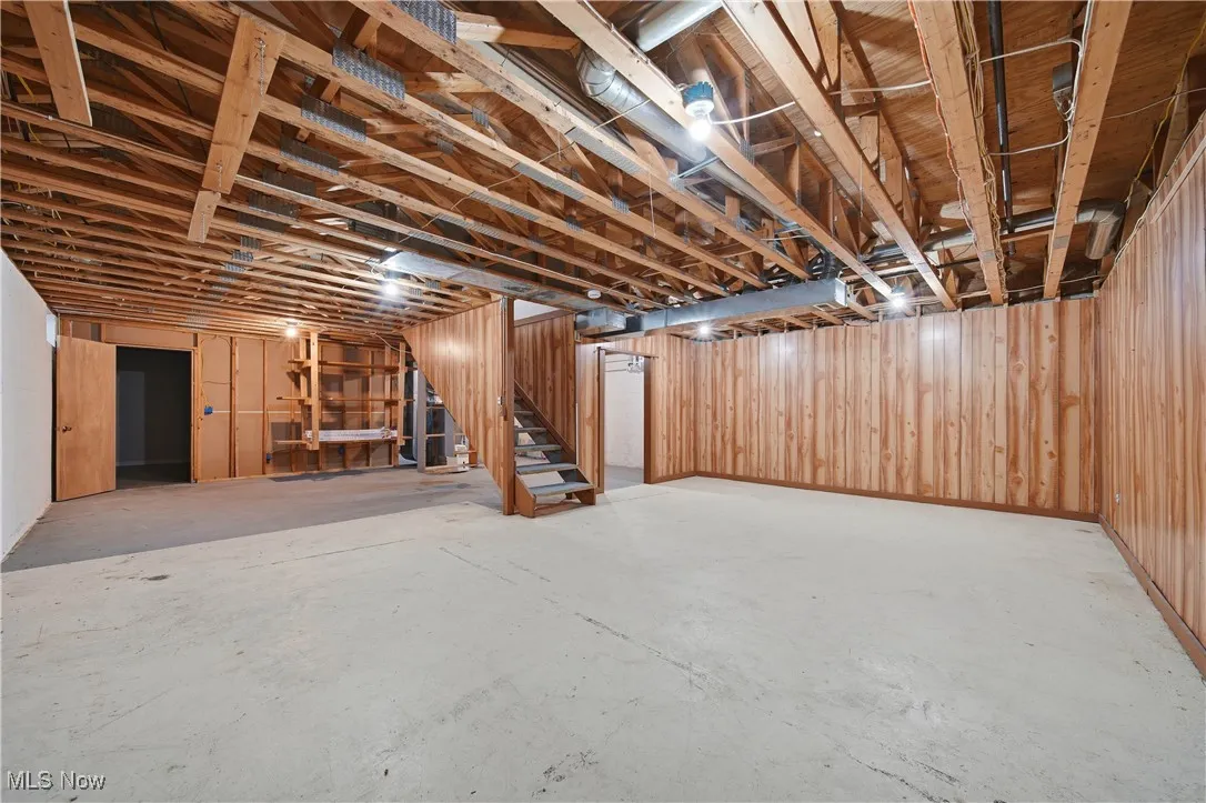 Unfinished basement featuring wood walls and stairway