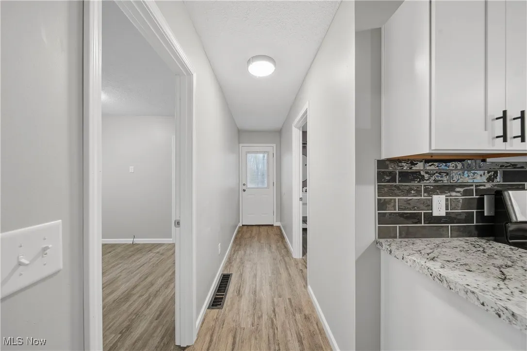Corridor featuring light wood-style floors and a textured ceiling