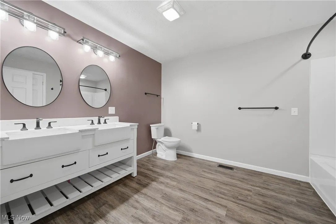 Full bathroom with tub / shower combination, double vanity, and light wood-style flooring