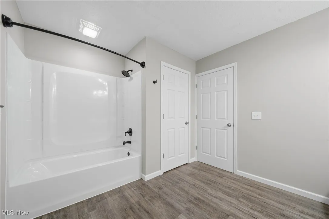 Full bath with bathing tub / shower combination and wood finished floors