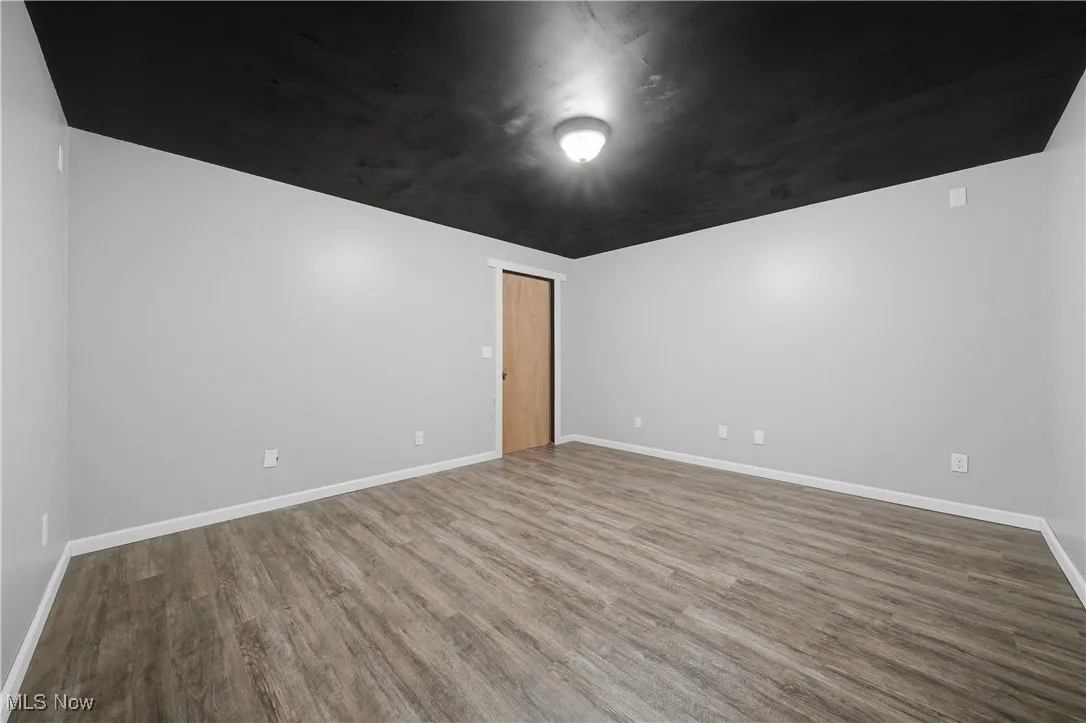 Unfurnished room with dark wood finished floors and baseboards