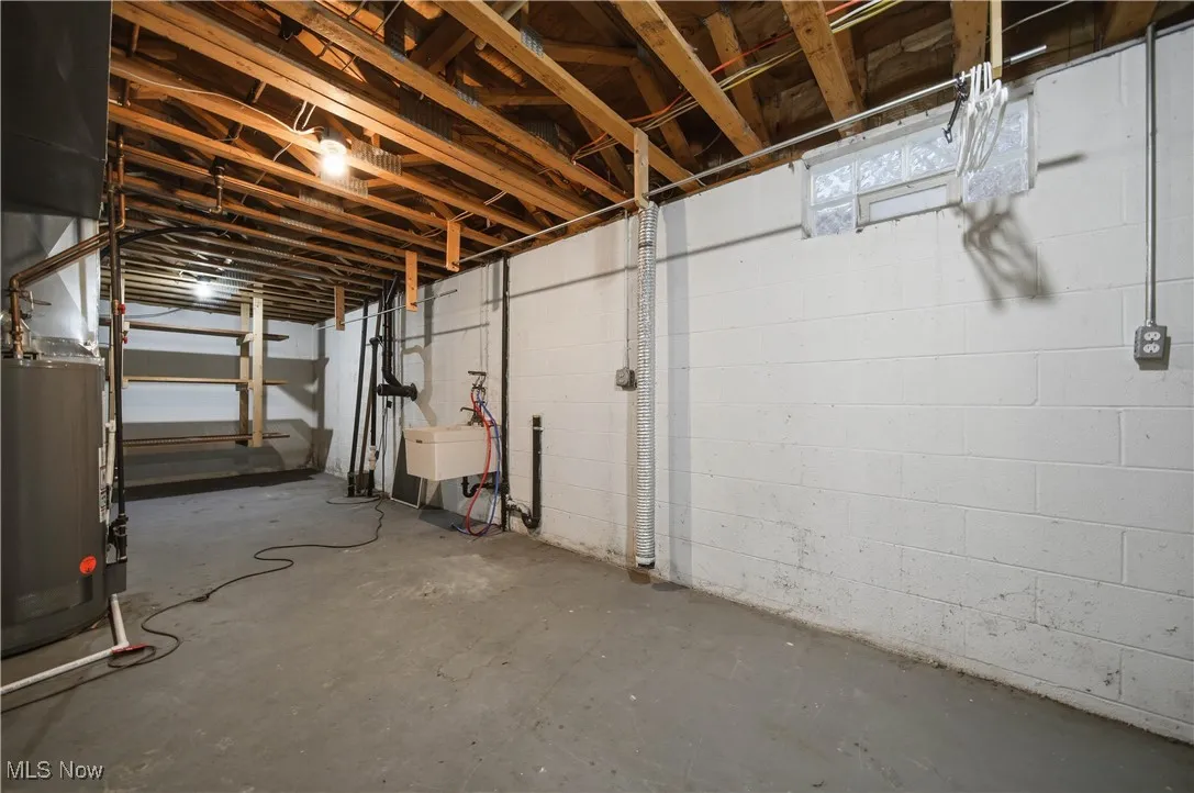 Unfinished basement featuring water heater and a sink