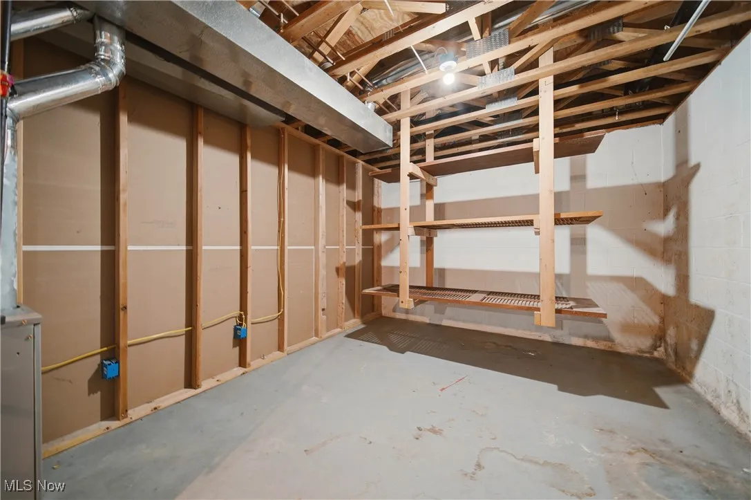 Unfinished basement featuring concrete block wall