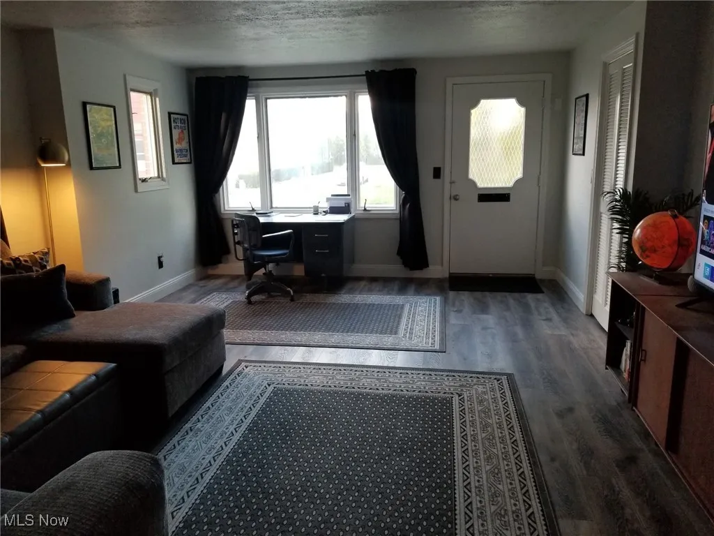 Living room featuring a desk, dark wood-style flooring, and a textured ceiling