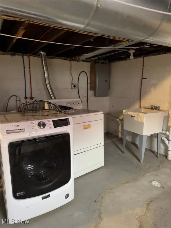 Laundry room featuring unfinished concrete flooring, electric panel, and washer and clothes dryer
