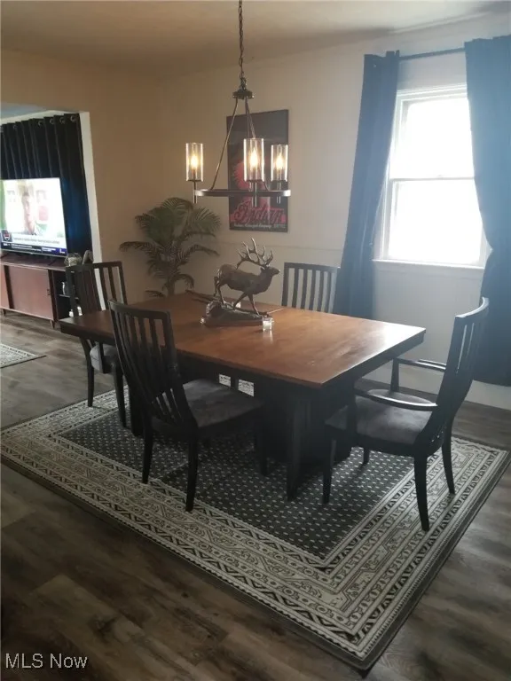 Dining room featuring dark wood-style floors and a chandelier