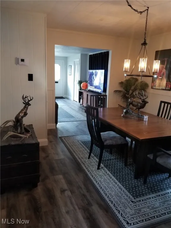 Dining room featuring dark wood-style flooring and a chandelier
