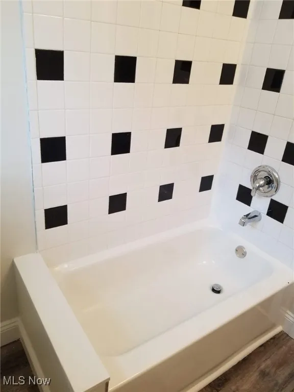 Bathroom featuring dark wood-style flooring and  shower combination
