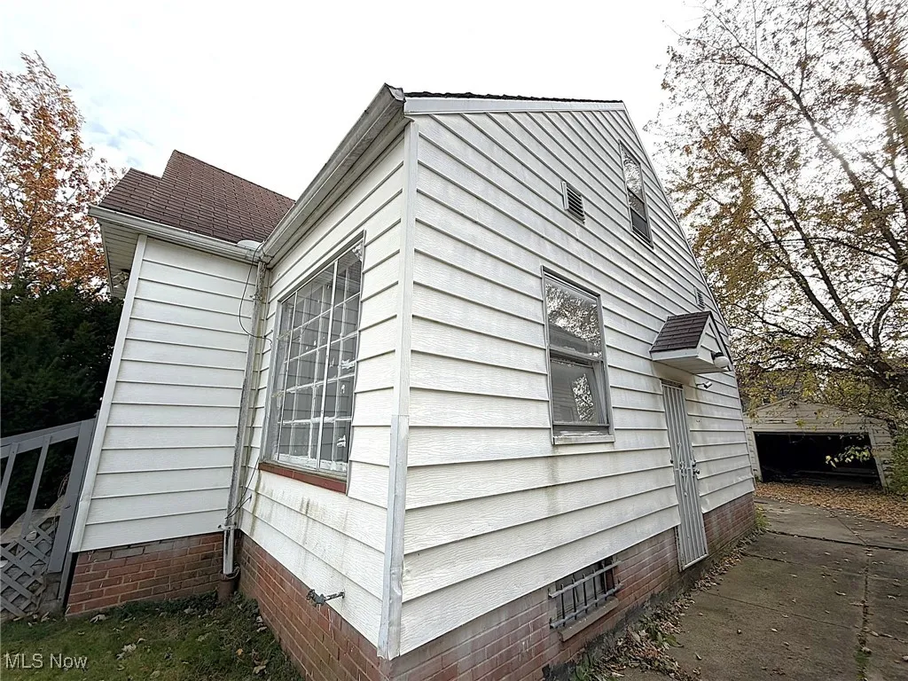 View of property exterior with crawl space, a garage, an outbuilding, and roof with shingles