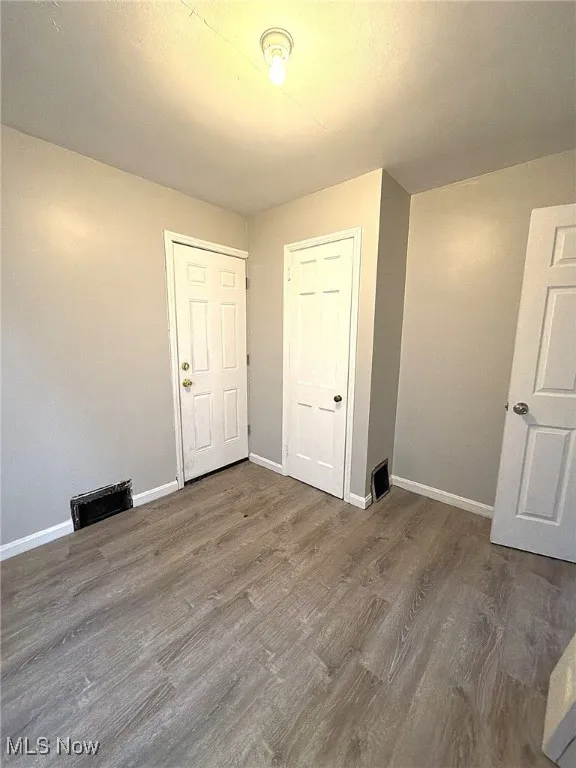 Unfurnished bedroom with wood finished floors and baseboards