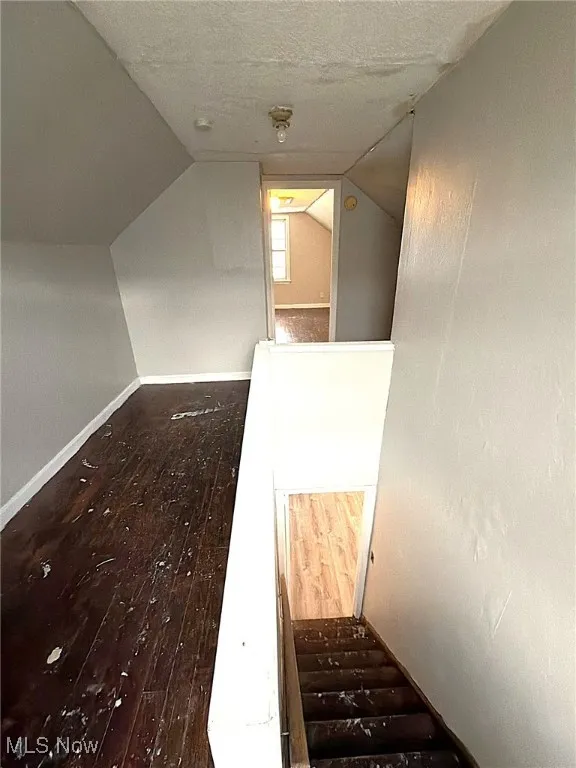Staircase with a textured ceiling and wood-type flooring