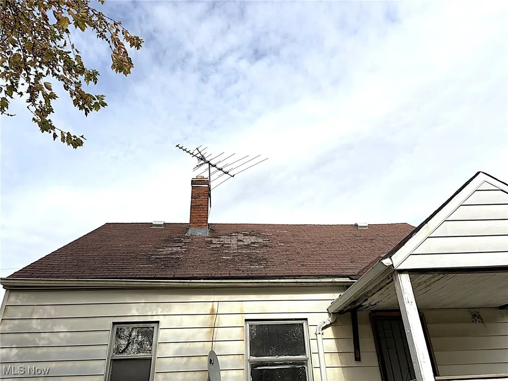 Exterior view of a chimney, roof with shingles, and gutters