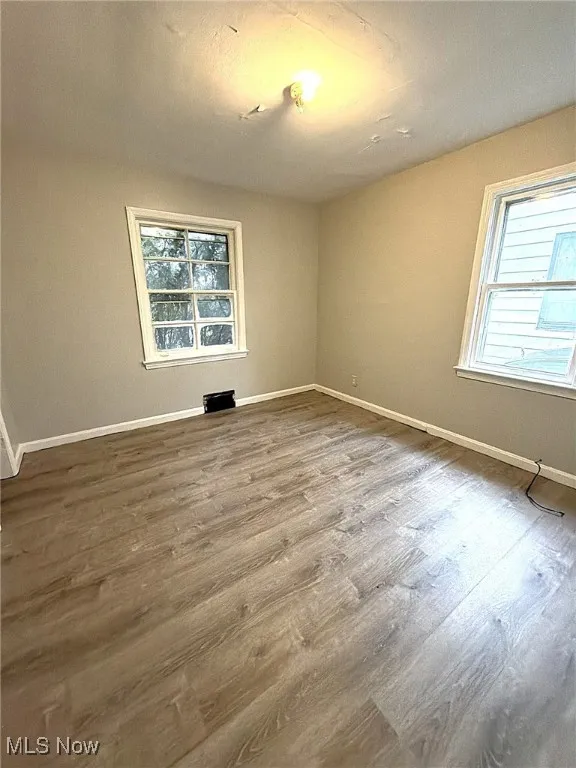 Unfurnished room featuring healthy amount of natural light and wood finished floors