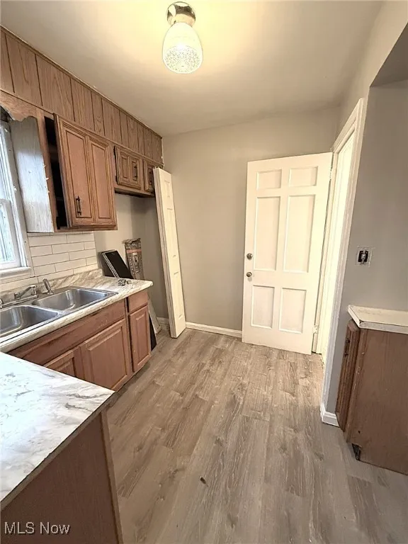 Kitchen featuring light countertops, brown cabinetry, tasteful backsplash, and light wood-type flooring