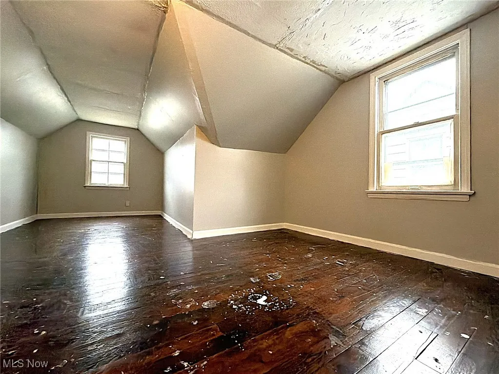 Bonus room with lofted ceiling and dark wood-style floors