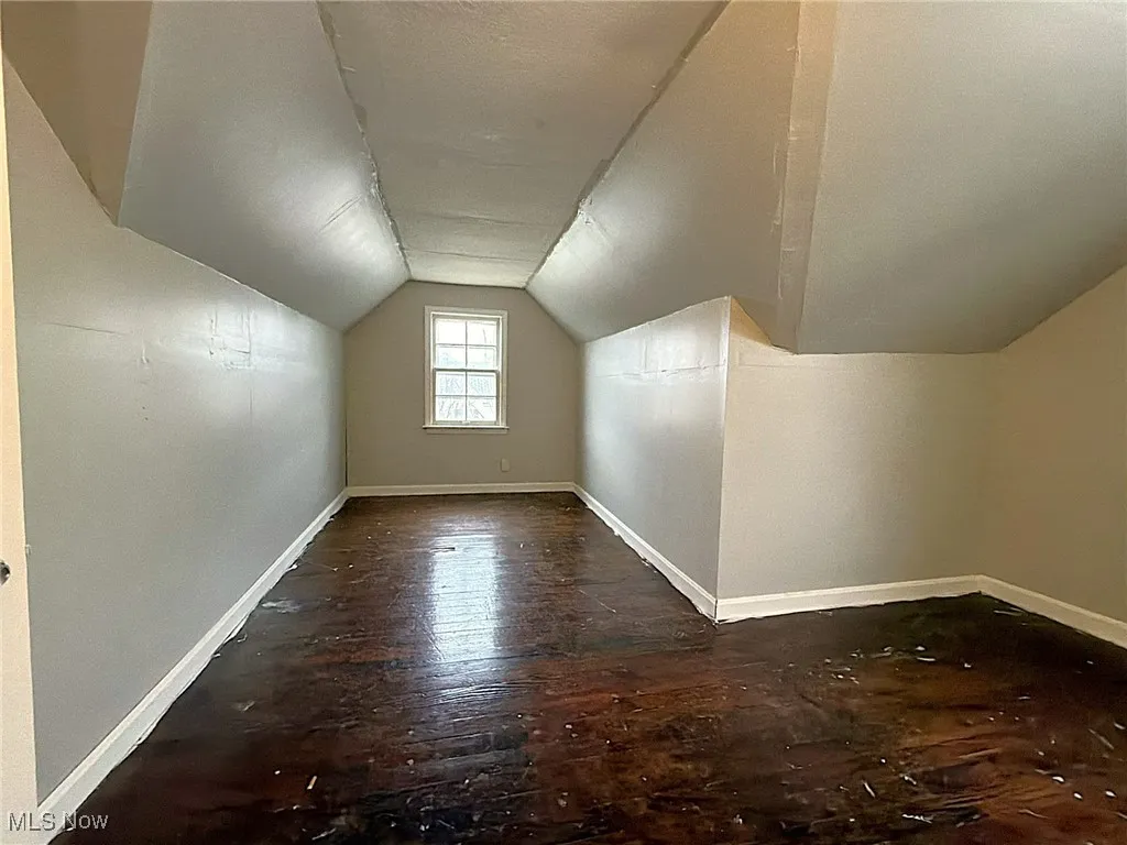 Bonus room with dark wood-style floors, lofted ceiling, and a textured ceiling