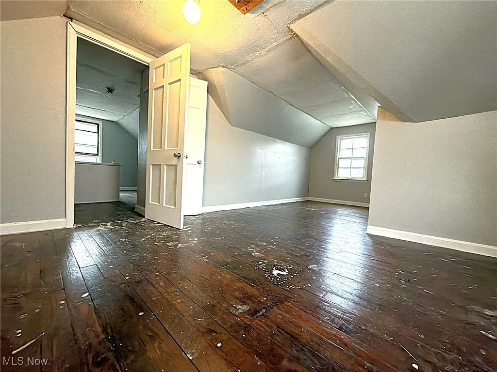 Bonus room with vaulted ceiling, dark wood finished floors, plenty of natural light, and a textured ceiling