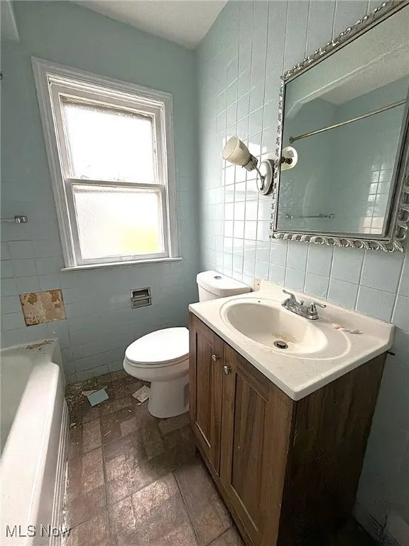 Bathroom with tile walls, vanity, and stone tile flooring