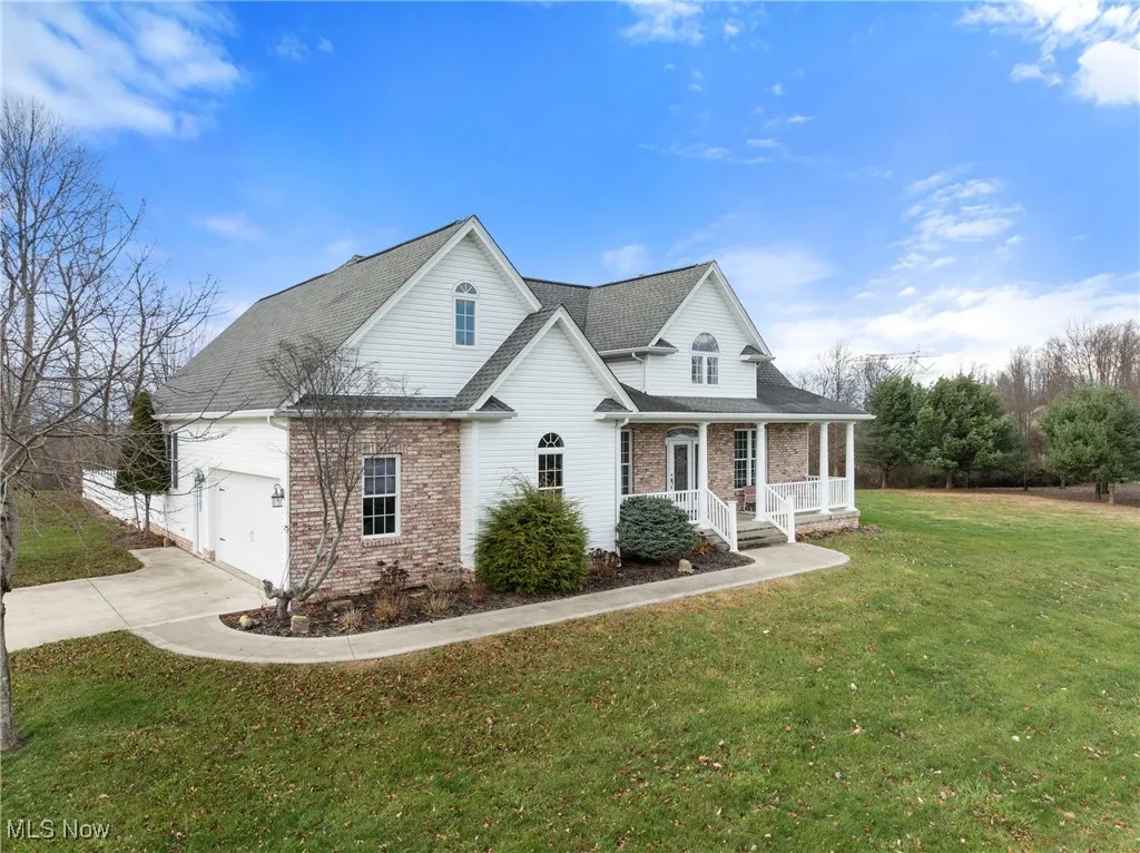 Traditional home with brick siding, roof with shingles, a porch, and concrete driveway