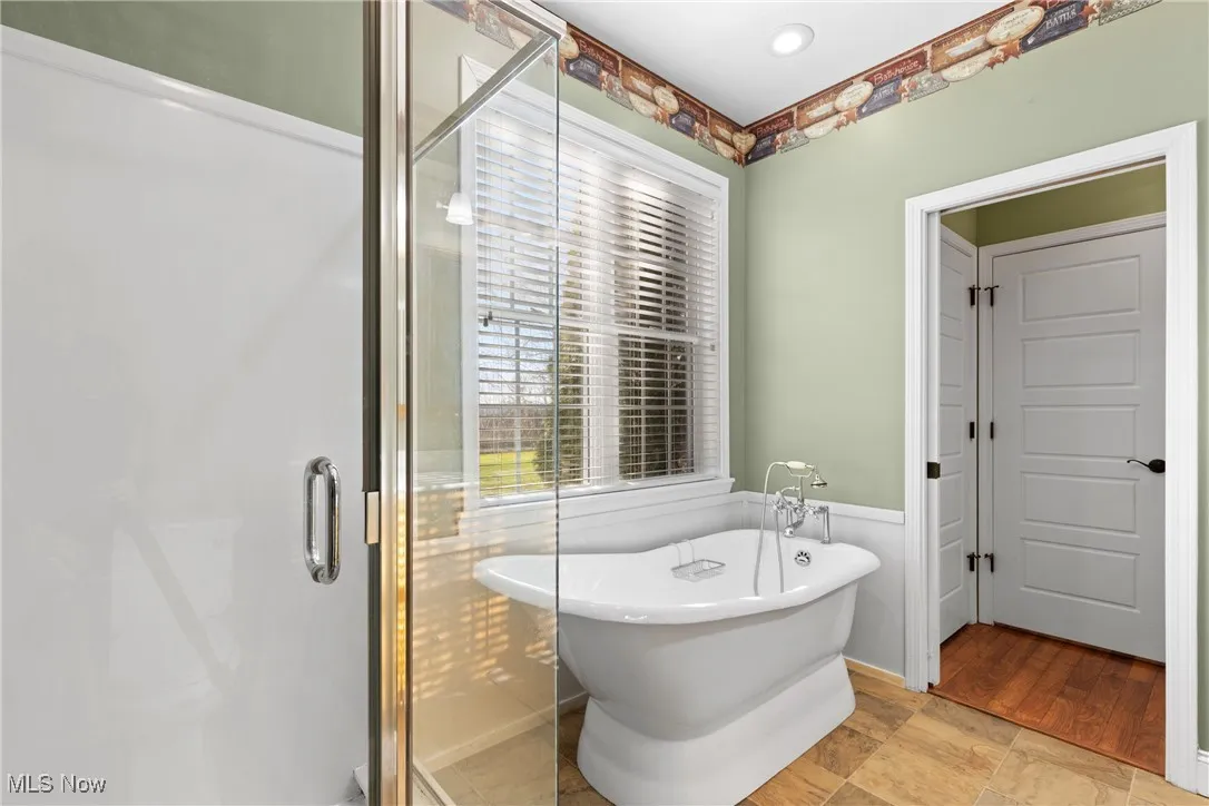 Master full bath featuring a freestanding tub, a stall shower, and a wainscoted wall