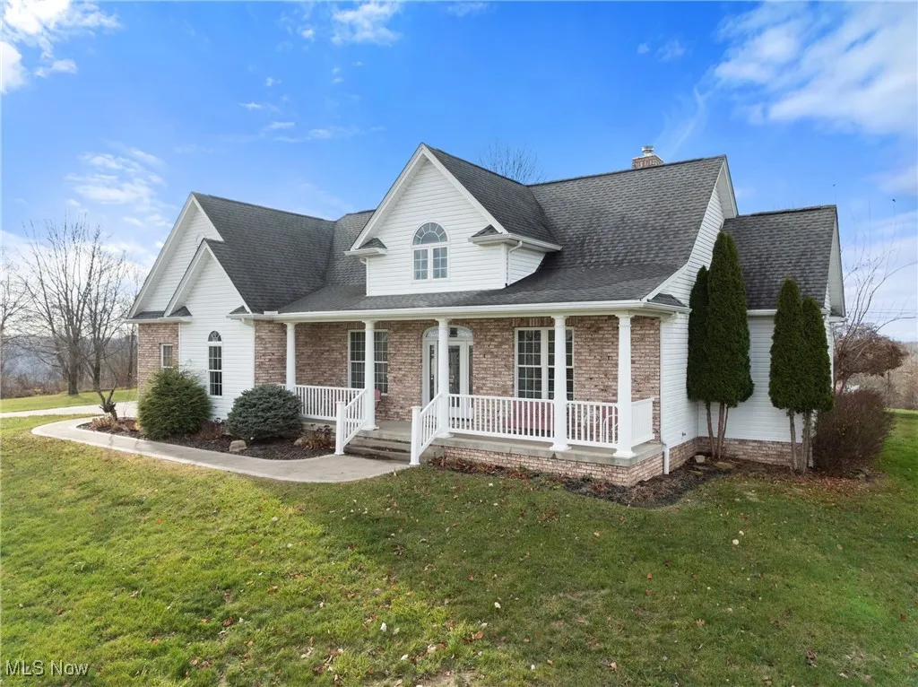 View of front of house featuring a porch, a shingled roof, and a front yard