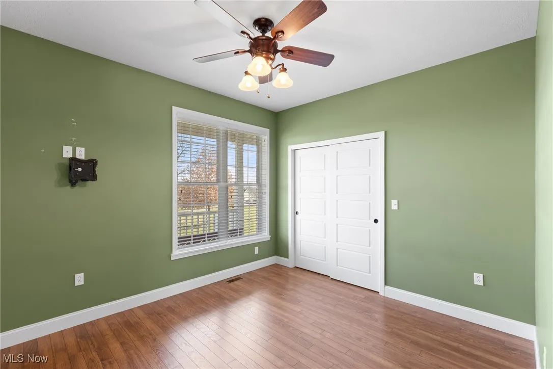 Unfurnished bedroom featuring hardwood / wood-style flooring, ceiling fan, and a closet