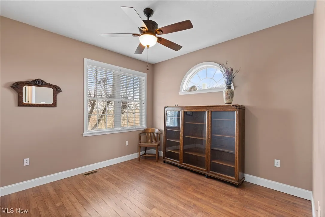 Sitting room with light wood-type flooring and a ceiling fan