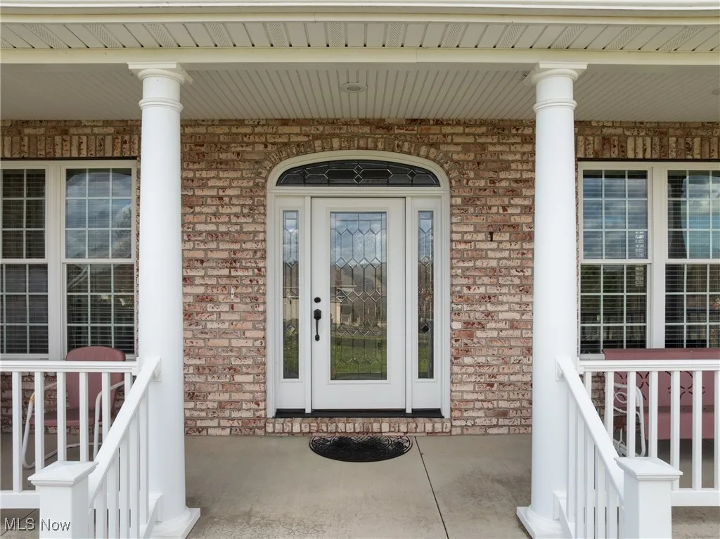 Property entrance with covered porch and brick siding