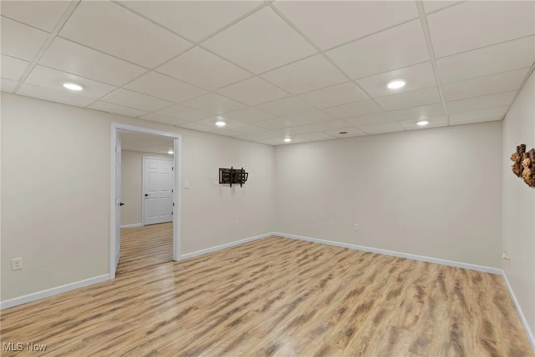 Finished below grade area featuring recessed lighting, light wood-style floors, and a drop ceiling