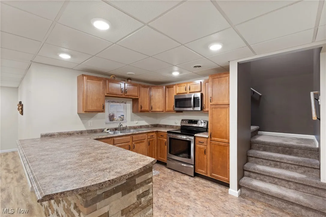 2nd Kitchen in basement with stainless steel appliances, a drop ceiling, light countertops, brown cabinets, and recessed lighting
