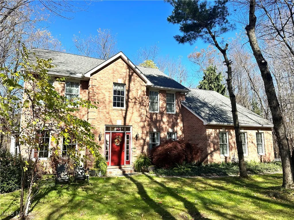 View of front of home with a front yard, brick siding, and a shingled roof