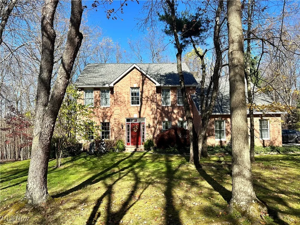 Colonial inspired home featuring brick siding, a front yard, and roof with shingles