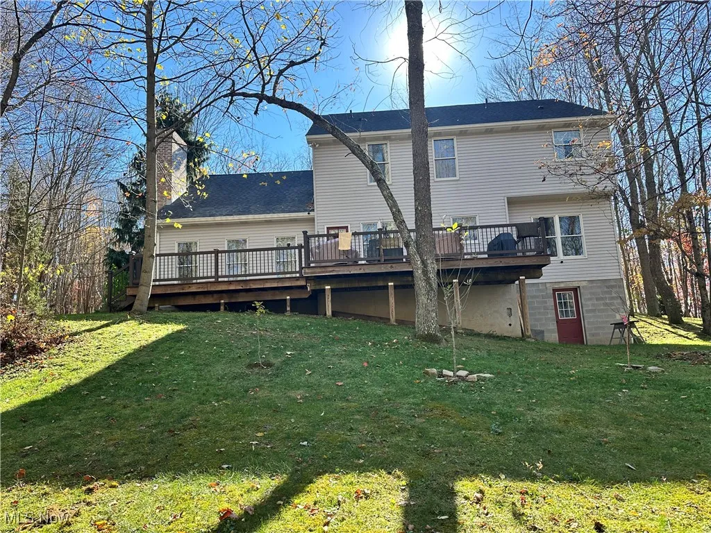 Rear view of property with a lawn, a deck, and a chimney