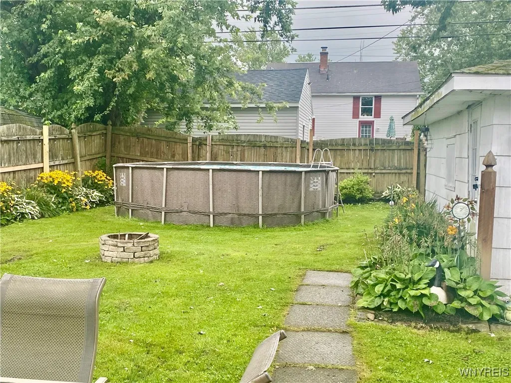 Fenced in back yard has a fire pit and above ground pool.