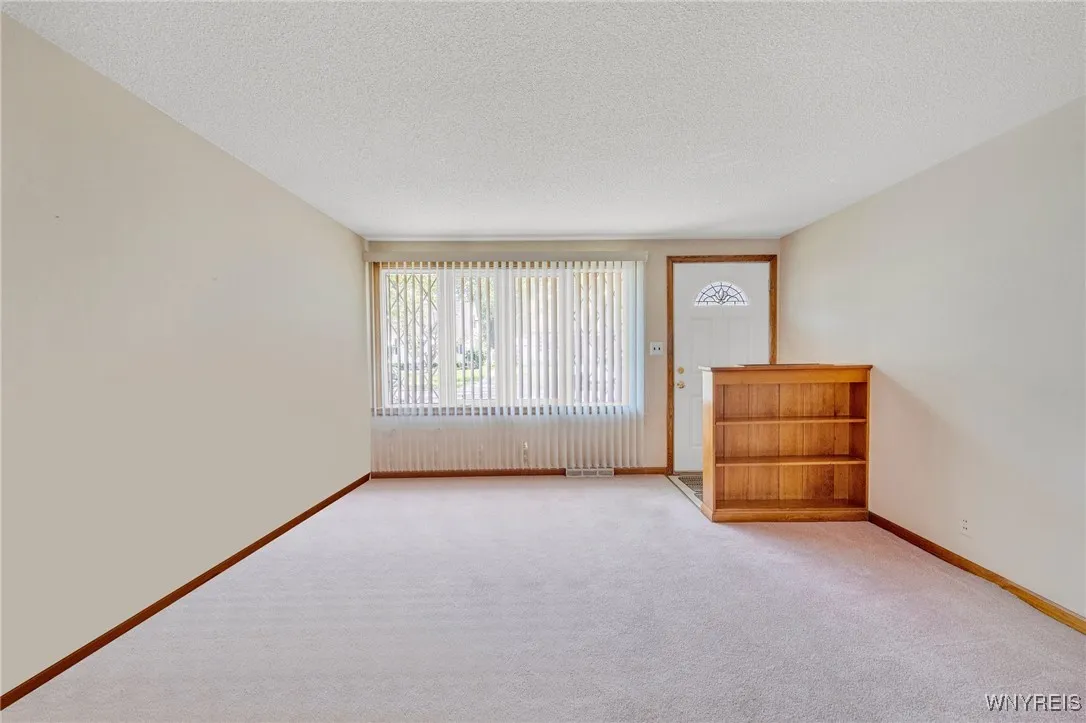 Living room with newer entrance door and window.