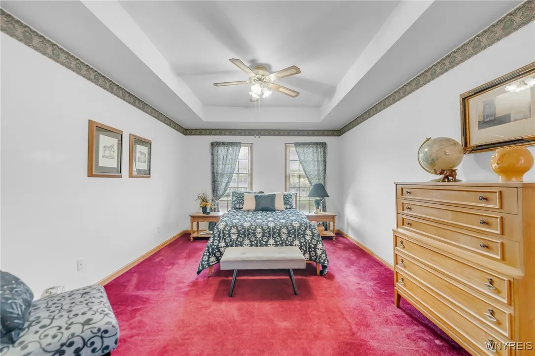 Primary Bedroom with tray ceiling with fan.