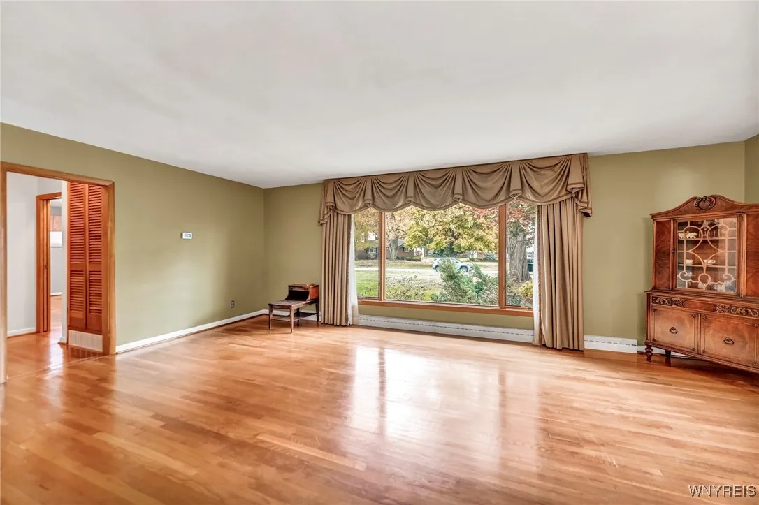 Very large living room with beautiful hardwoods and a newer window.