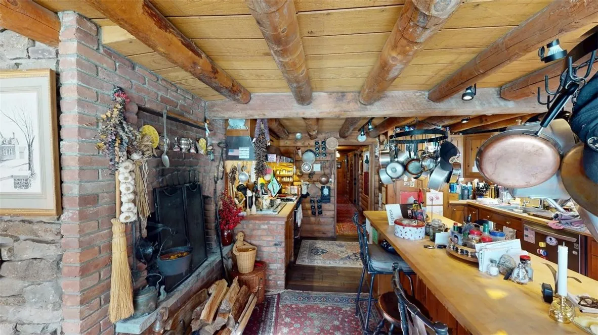 From the dining area looking into the kitchen. The hall leading to the entry and primary bedroom is in the distance. Note the brick hearth and fireplace.