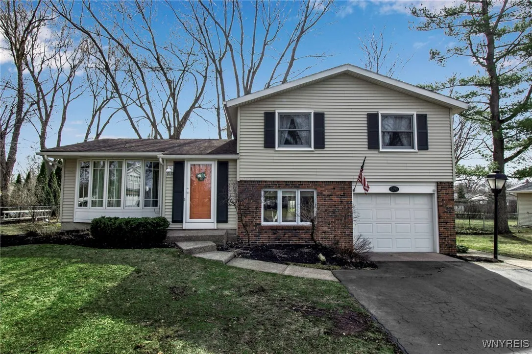 Front view of vinyl + brick home w/blacktop driveway + concrete walkway to front entrance