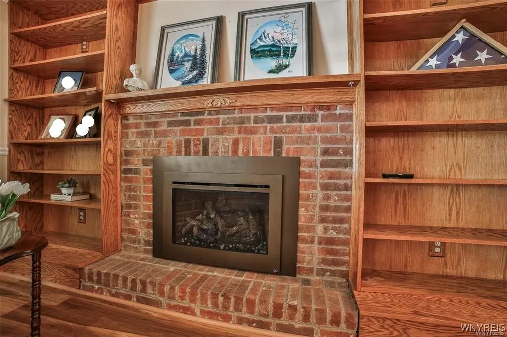 Raised hearth, brick, gas fireplace flanked on both sides with custom bookshelves and mantle.