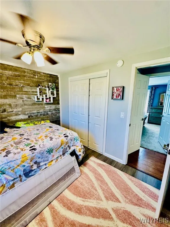 2nd bedroom with shiplap wall, ceiling fan and large closet.