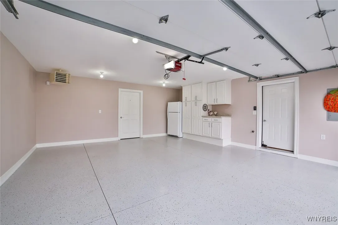 Spotless Heated Garage Interior, Epoxy Floor, Painted, Baseboard Molding, Countertop and Cabinetry additions, Refrigerator, Door to Extra Storage Space.