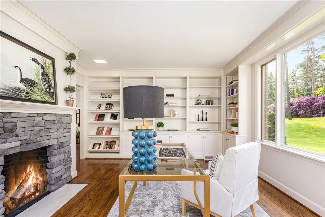 The library boasts a wood burning fireplace, incredible views of the front yard and landscaping, and walls of bookcases.