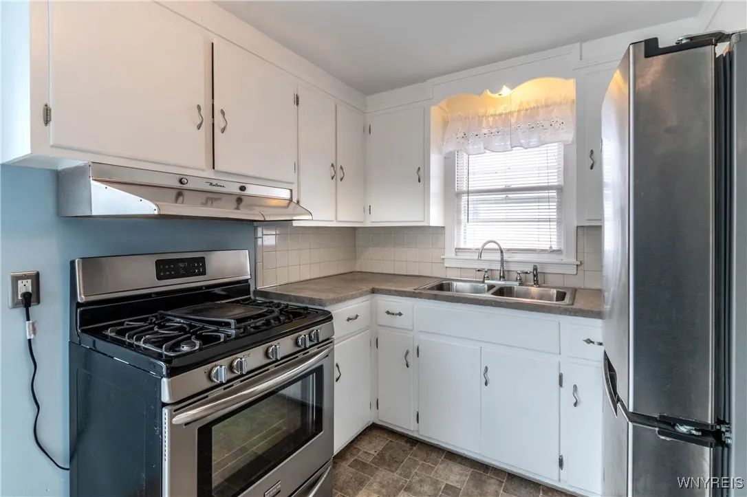 Cozy kitchen has nice stainless steel range and refrigerator