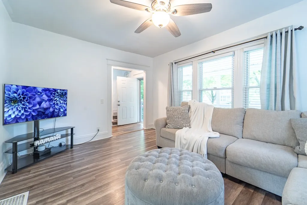 The living room boasts  luxury vinyl flooring and expansive walls of windows, filling the space with natural light and a bright, open ambiance.