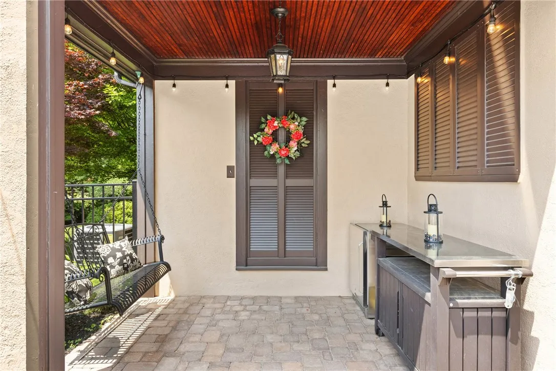 The outdoor covered kitchen is perfect for entertaining, complete with built-in fridge and generous counter space. A charming swing adds a relaxing touch to this backyard retreat.