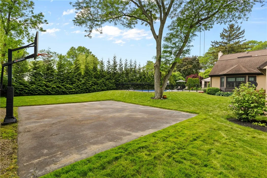 The backyard features a dedicated basketball court and a spacious grassy area, ideal for outdoor sports, games, and active play.