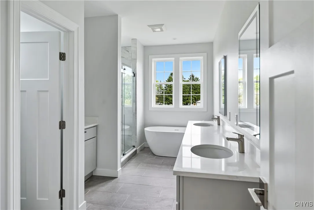 Primary suite bath with double vanity, shower, tub, separate storage vanity and toilet room to the left.